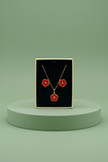 Hand holding a black jewelry box with red floral earrings and necklace.