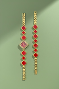 Bracelets with red and gold design on a branded card held by a hand outdoors.